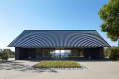 a black building with lots of windows and plants in the front yard on a sunny day