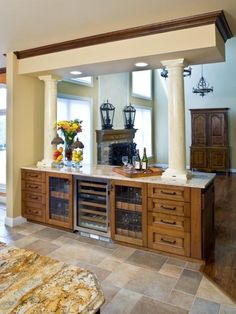 a large kitchen with marble counter tops and wooden cabinets in front of an open fireplace