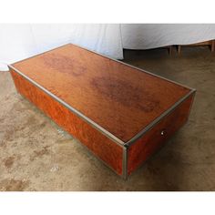 a large wooden box sitting on the floor next to a white sheet covered tablecloth