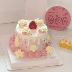 a white cake with pink icing and flowers on it next to a yellow cookie