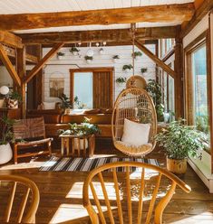 a living room filled with lots of furniture and plants on top of wooden flooring