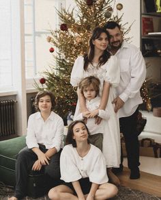 a family poses in front of a christmas tree