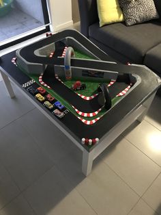 a table that has a race track set on top of it in front of a couch