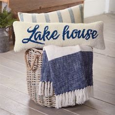 a basket filled with towels and pillows sitting on top of a wooden floor next to a bench