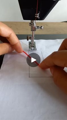 someone is using a sewing machine to sew something on the paper with red thread