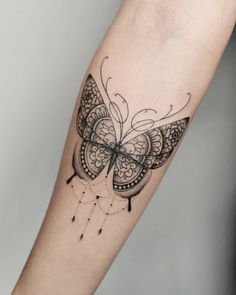 a black and white butterfly tattoo on the right arm, with dots around it's wings