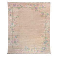 an antique rug with flowers and leaves on the border, in pale pink tones against a white background