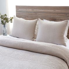 a bed with white sheets and pillows in a bedroom