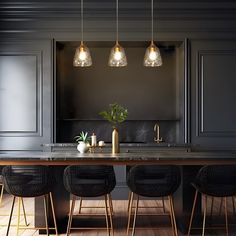 a kitchen with black walls and wooden floors, three lights hanging over the island counter