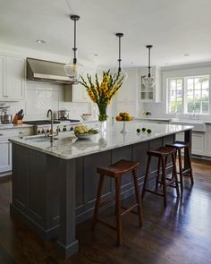 a large kitchen island with stools next to it and yellow flowers in the center