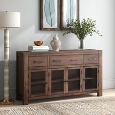 a sideboard with two mirrors above it and a lamp on the floor next to it