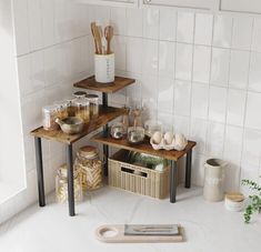 three wooden tables with baskets and utensils on them in a white tiled kitchen