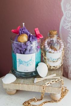 two small bottles with seashells in them sitting on a wooden table next to a chain