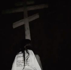 a woman standing in front of a cross with her back turned to the camera and words written on it