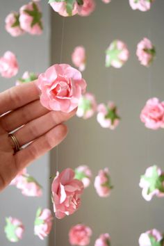 a hand is holding pink flowers in the air