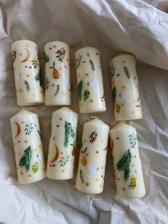 six candles with designs on them sitting on a sheet