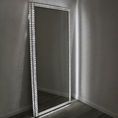 a large mirror sitting on top of a wooden floor next to a white wall in an empty room