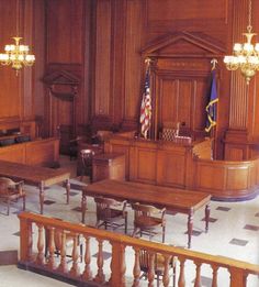 an empty courtroom with wooden tables and chairs