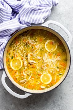 a pot filled with chicken and lemon soup on top of a table next to a blue towel