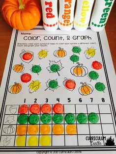 a pumpkin themed color count and graph game on a table next to some candy tubes