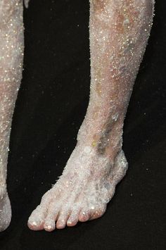 the legs and feet of a woman covered in white glitters on a black background