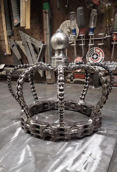 a metal crown sitting on top of a table in a room filled with other tools