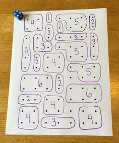 a piece of paper with numbers and dices on it sitting on a wooden table