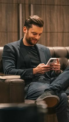 a man sitting on a couch looking at his cell phone