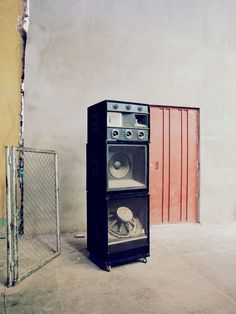 two speakers are stacked on top of each other in front of a red and white wall