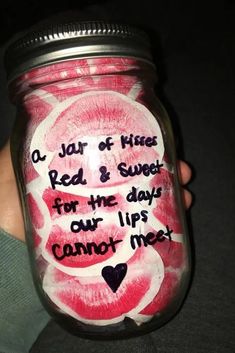 a person holding a mason jar with writing on it and hearts painted on the lid