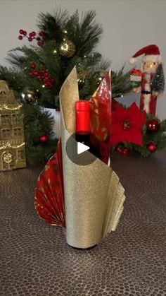 a wine bottle wrapped in gold paper next to a christmas tree