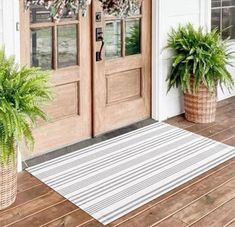 two potted plants sitting on the front porch next to an entryway mat and door