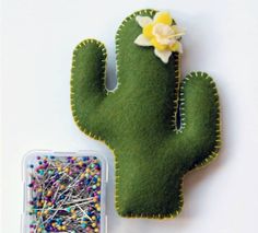 a cactus pin cushion next to a container with pins