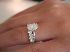 a woman's hand with a diamond ring on top of her finger and an engagement band