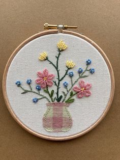 a small vase filled with flowers sitting on top of a wooden table next to a wall