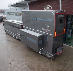 a horse trailer parked in front of a building with its doors open and windows closed