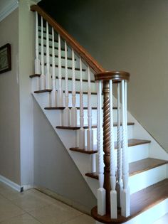 a white staircase with wooden handrails and tile flooring