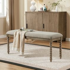 a wooden bench sitting on top of a rug in front of a cabinet and window