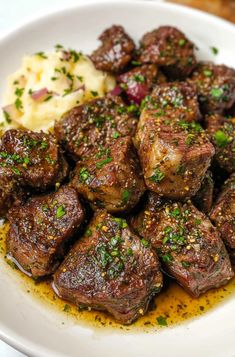 a white plate topped with meat and potatoes covered in seasoning next to a fork