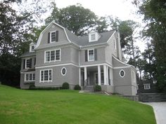 a large gray house sitting on top of a lush green field