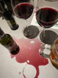 three glasses of wine are sitting next to each other on a table with red stain