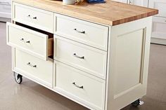 a kitchen island with drawers on wheels in front of white cabinets