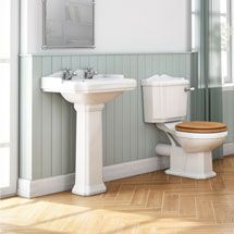 a white toilet sitting next to a sink in a bathroom on top of a hard wood floor