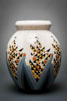 a white vase with orange and black designs on the outside, sitting on a gray surface