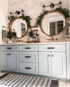 a bathroom with two round mirrors on the wall and wreaths in the mirror above it