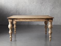 an old wooden table sitting on top of a cement floor next to a gray wall