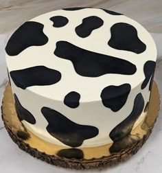 a cake decorated with black and white cow print on top of a gold plated platter