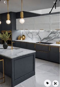 a kitchen with marble counter tops and gold accents on the cabinets, along with two pendant lights hanging from the ceiling