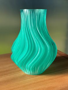 a green vase sitting on top of a wooden table