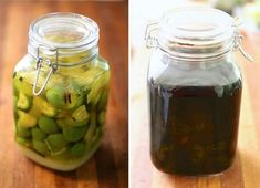 two jars filled with pickles on top of a wooden table next to each other